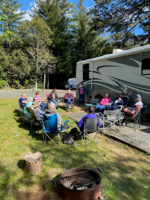 Group of people gathered in lawn chairs outside a motorhome.